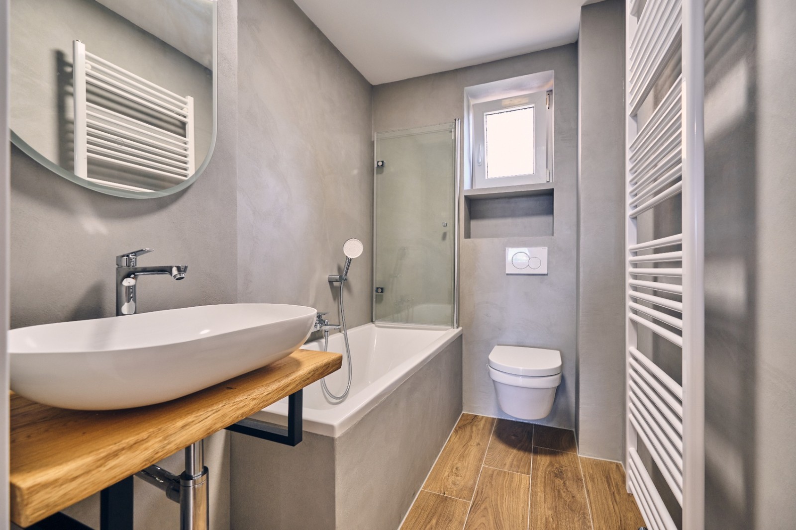 Neu saniertes Bad mit Aufsatzwaschbecken, Badewanne mit Duschwand und Holzoptik-Fliesen