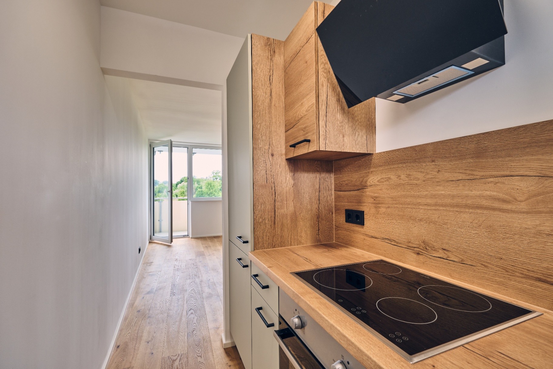 Detailansicht Küche mit Holzfronten, Induktionskochfeld und Balkon im Hintergrund